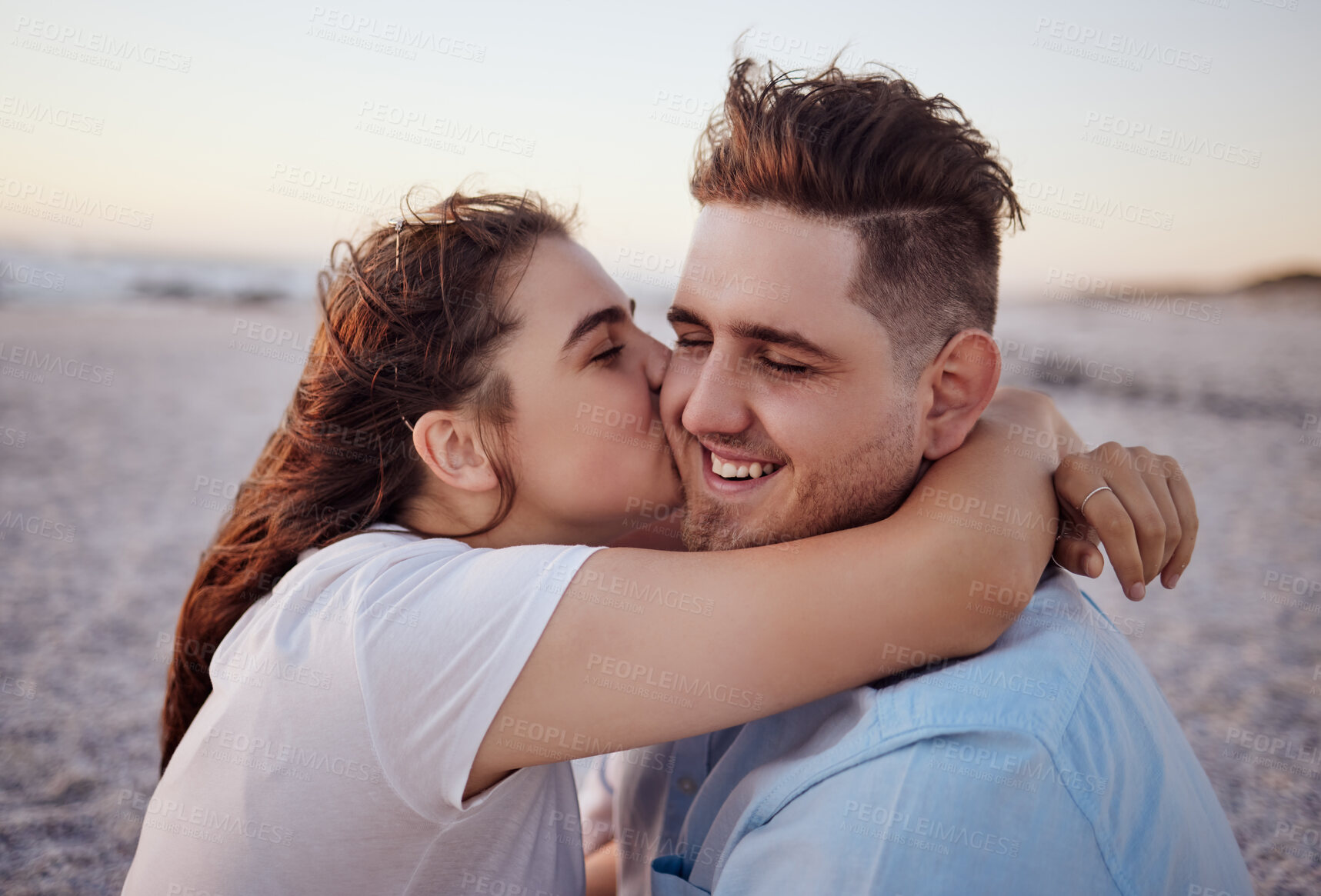 Buy stock photo Love, couple and kiss on beach happy to celebrate relationship with sunset being relax, smile and on holiday. Romance, man and woman hug, embrace and bonding on seaside vacation together outdoor. 