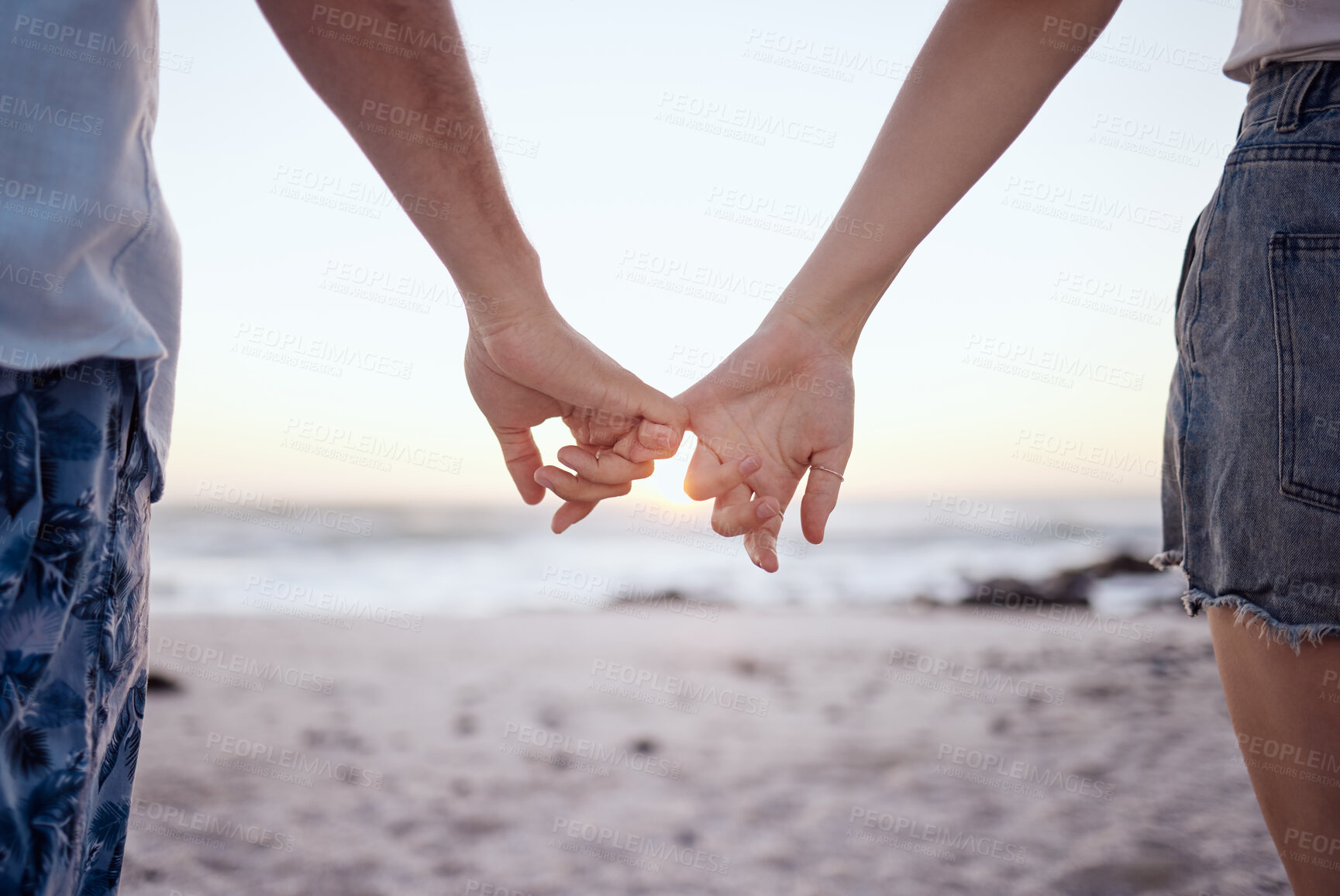 Buy stock photo Love, couple and holding hands on beach and sand for relationship, anniversary and embrace while on holiday together. Romance, man and woman happy, loving and bonding with sunset on vacation and trip