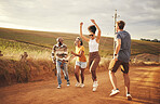 Friends, freedom and fun with a man and woman group outdoor in the desert on a sand road in nature. Travel, summer and vacation with young people enjoying a holiday together while laughing or joking