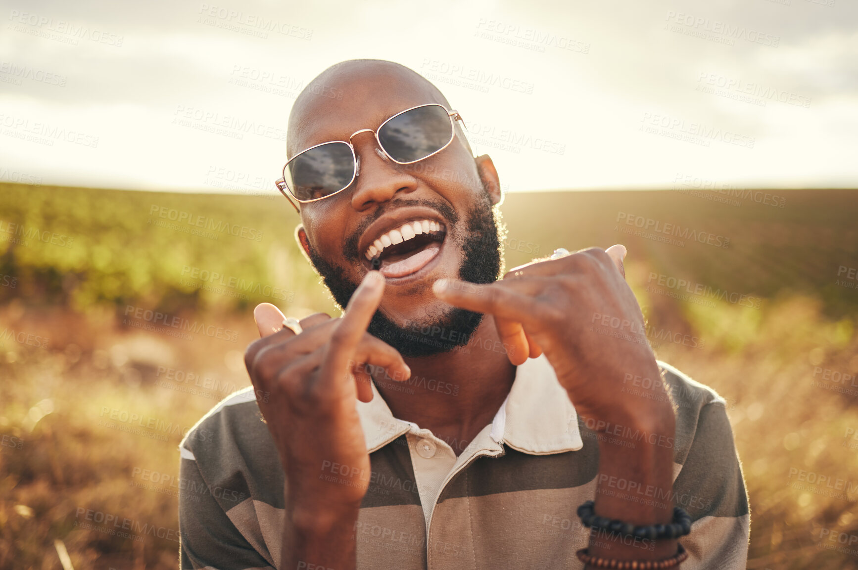 Buy stock photo Hand sign, freedom and summer with a black man enjoying nature outdoor alone during the day. Shaka, happy and carefree with a young male outside posing outside with a cheerful expression of fun