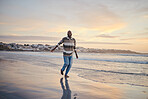 Beach, freedom and vacation with a black man by the ocean or sea, running on sand with a sunset view of the sky and horizon. Nature, water and summer with a young male enjoying a holiday on the coast