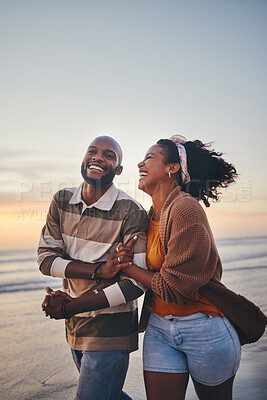 Buy stock photo Happy couple, love and travel at the beach holding hands on date, quality time and romance at sunset. Black woman and man, laughing and walking together by the ocean on honeymoon during summer. 