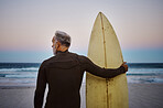 Beach, man and surfboard with back view for morning cardio fitness and tranquil swim in nature. Senior surfer waiting for low tide at ocean for calm surf waves with peaceful sky at dawn.