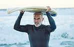 Senior man, ocean surfer and carrying surfboard on holiday, vacation or summer trip in Canada. Workout, fitness and retired male with board after surfing, water sports and training exercise by sea.
