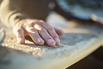 Hand, surfboard and sports with a man surfer cleaning sand from his board after surfing at the beach during summer. Sport, travel and vacation with a male outdoor in nature to surf, relax or have fun