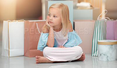 Buy stock photo Child, fashion and shopping bags while looking bored and waiting in a kids clothing shop, store or boutique with cute girl sitting on floor. Little kid shopper or customer with sale purchase packages