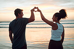 Beach, couple and heart hand at sunset with happy people bonding together on Mexico holiday break. Care, love and trust in interracial romantic relationship with people enjoying ocean sky at dusk.