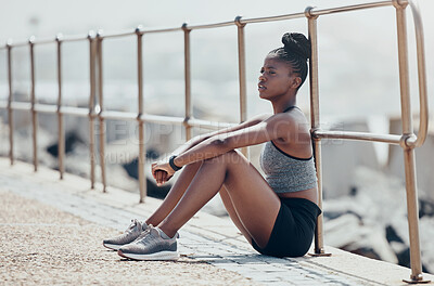 Buy stock photo Beach, relax and woman runner thinking after an outdoor cardio workout in nature by ocean. Tired African athlete, running and fitness girl sitting on promenade to breathe, calm and rest after workout