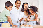 Mother, father and children learning baking as a happy family together teaching siblings to bake cakes. Mom, dad and kids cracking eggs, cooking and parents helping boy and girl in child development