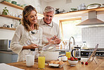 Elderly, couple and in kitchen while cooking, baking and happy together in funny moment. Senior man, woman and retirement smile in home, bonding and smile with love to make cookies, cake and bake