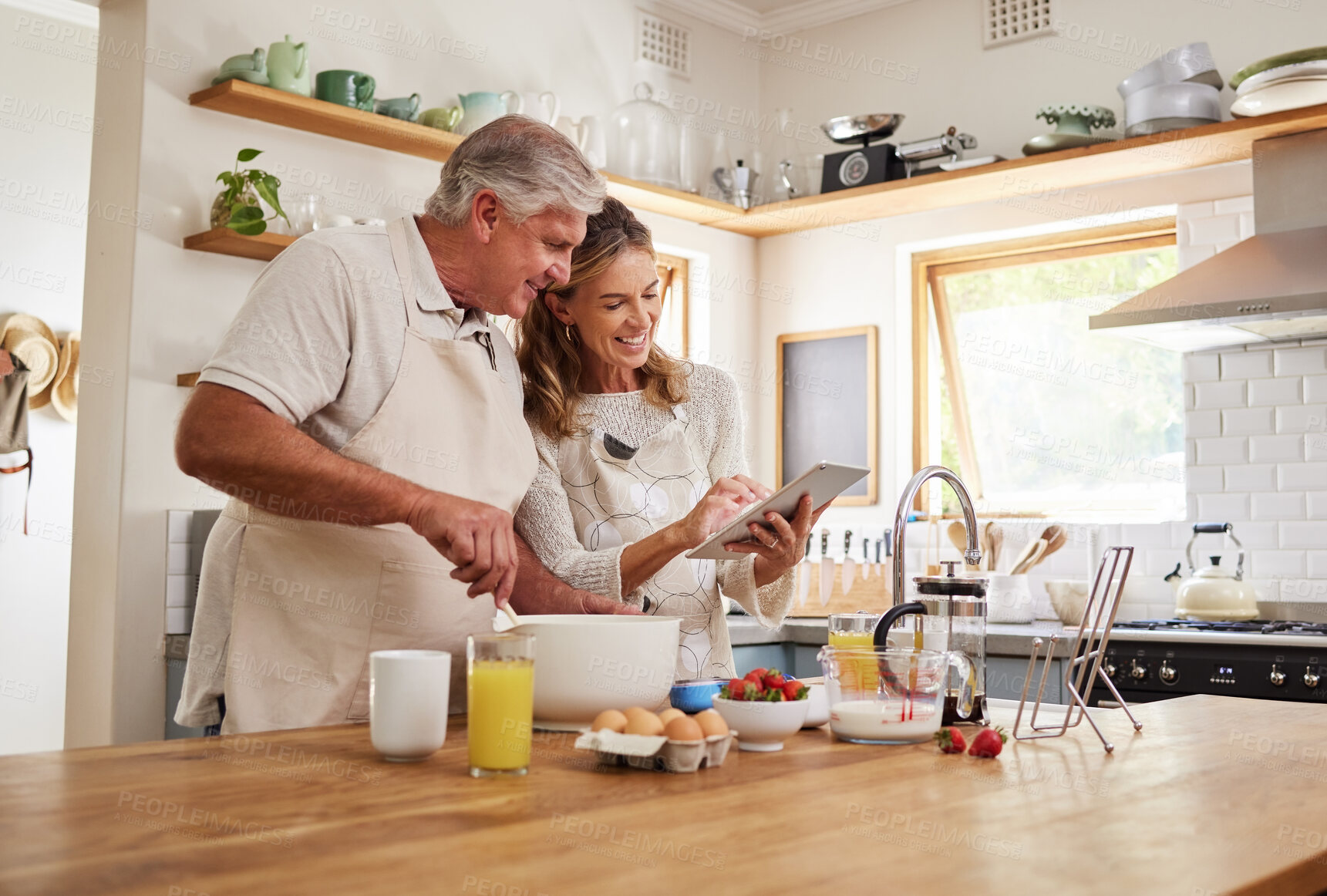 Buy stock photo Cooking, recipe and senior couple with tablet for online video for breakfast food in the kitchen of their house. Happy elderly man and woman reading on the internet with tech for healthy lunch