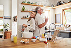 Senior couple, cook breakfast in kitchen and love making food together in their retirement time. Elderly people smile, cooking or baking pancakes and healthy meals at home with glass of orange juice 