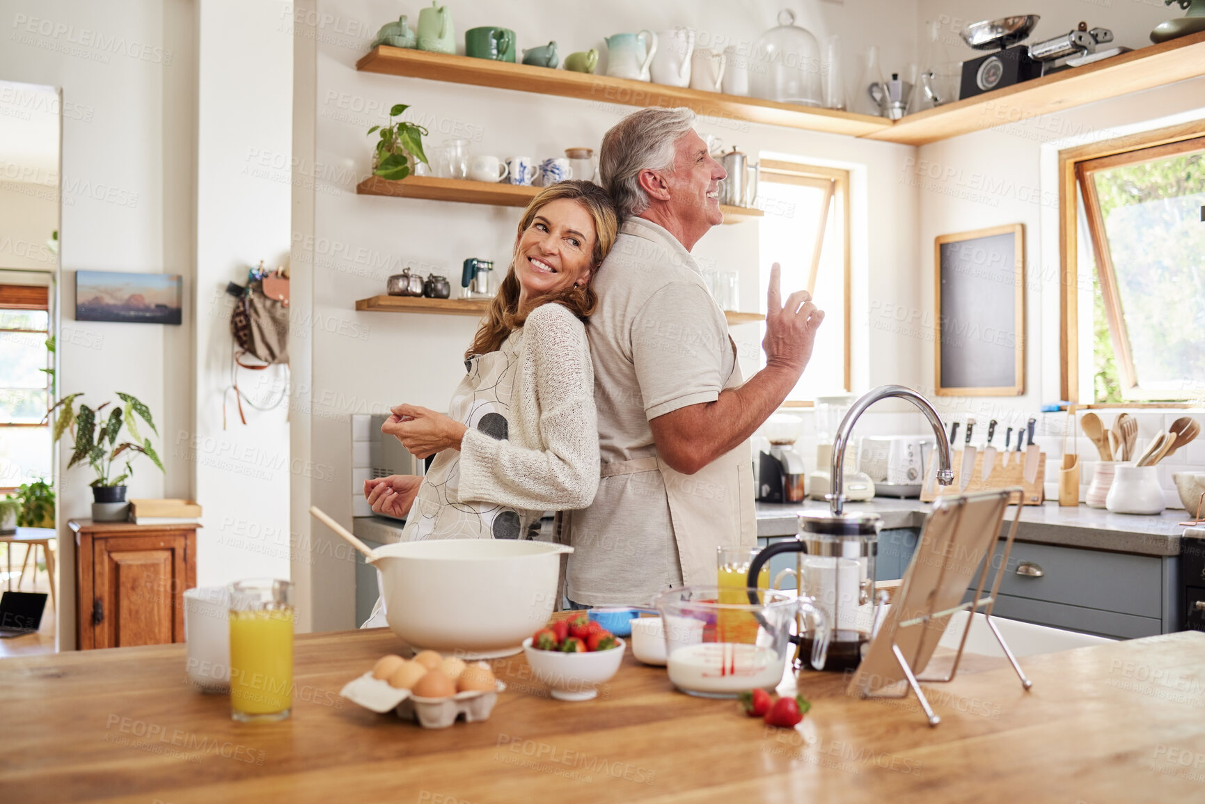 Buy stock photo Senior couple dance, cook breakfast in the kitchen and love making food together in retirement time. Elderly people smile, have fun cooking or baking pancakes and healthy meals while dancing at home 