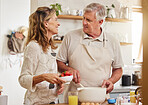 Elderly, couple and in kitchen for, baking with strawberry, egg and happy together in home. Older man, woman and retirement smile in home, talking and learning to make cookies, cake or dessert