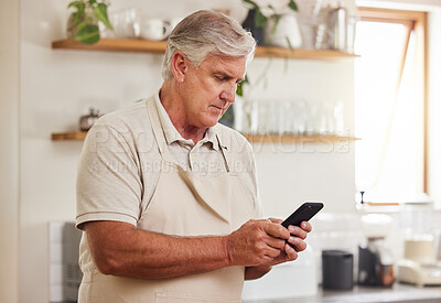 Buy stock photo Typing, phone and senior man reading an email on a mobile app during retirement in his house. Elderly person with calm and peace while on the internet with a smartphone in the kitchen of his home