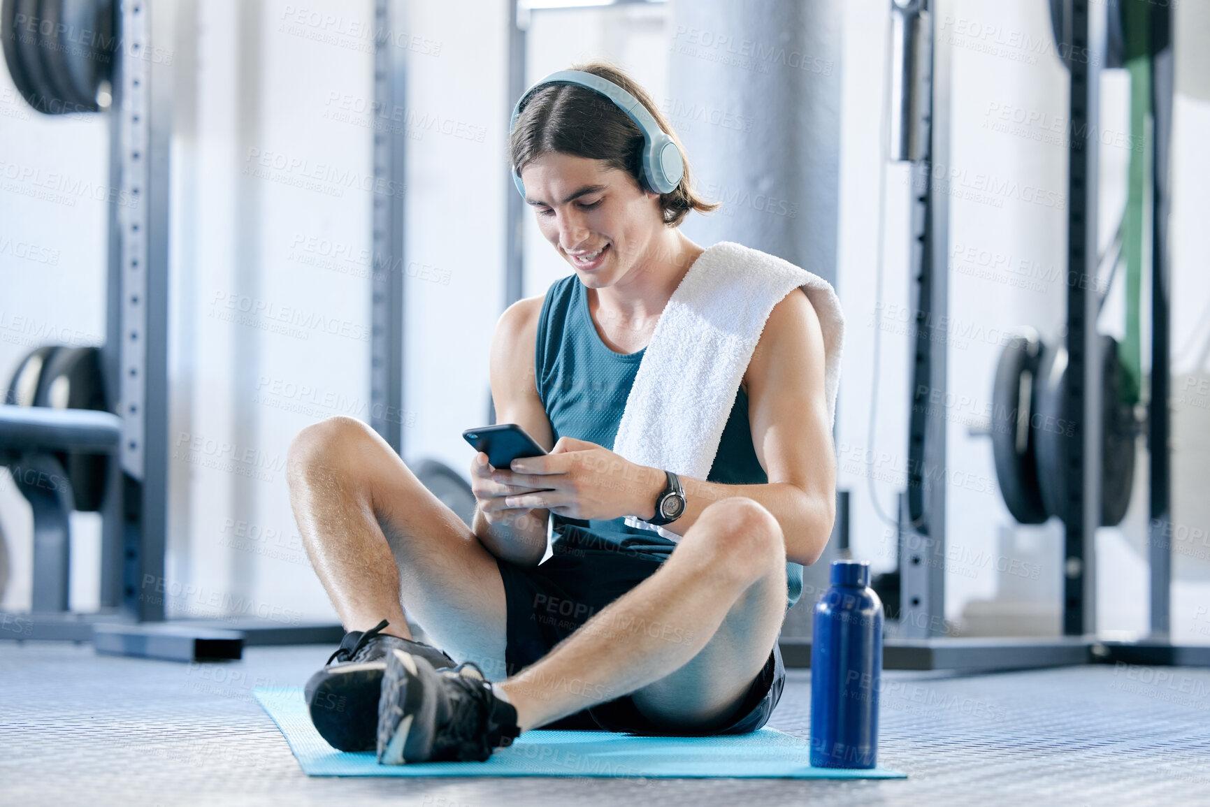 Buy stock photo Man check social media in gym, workout music playlist on smartphone and typing online conversation. Happy young athlete sitting on floor, sports health application and fitness lifestyle technology