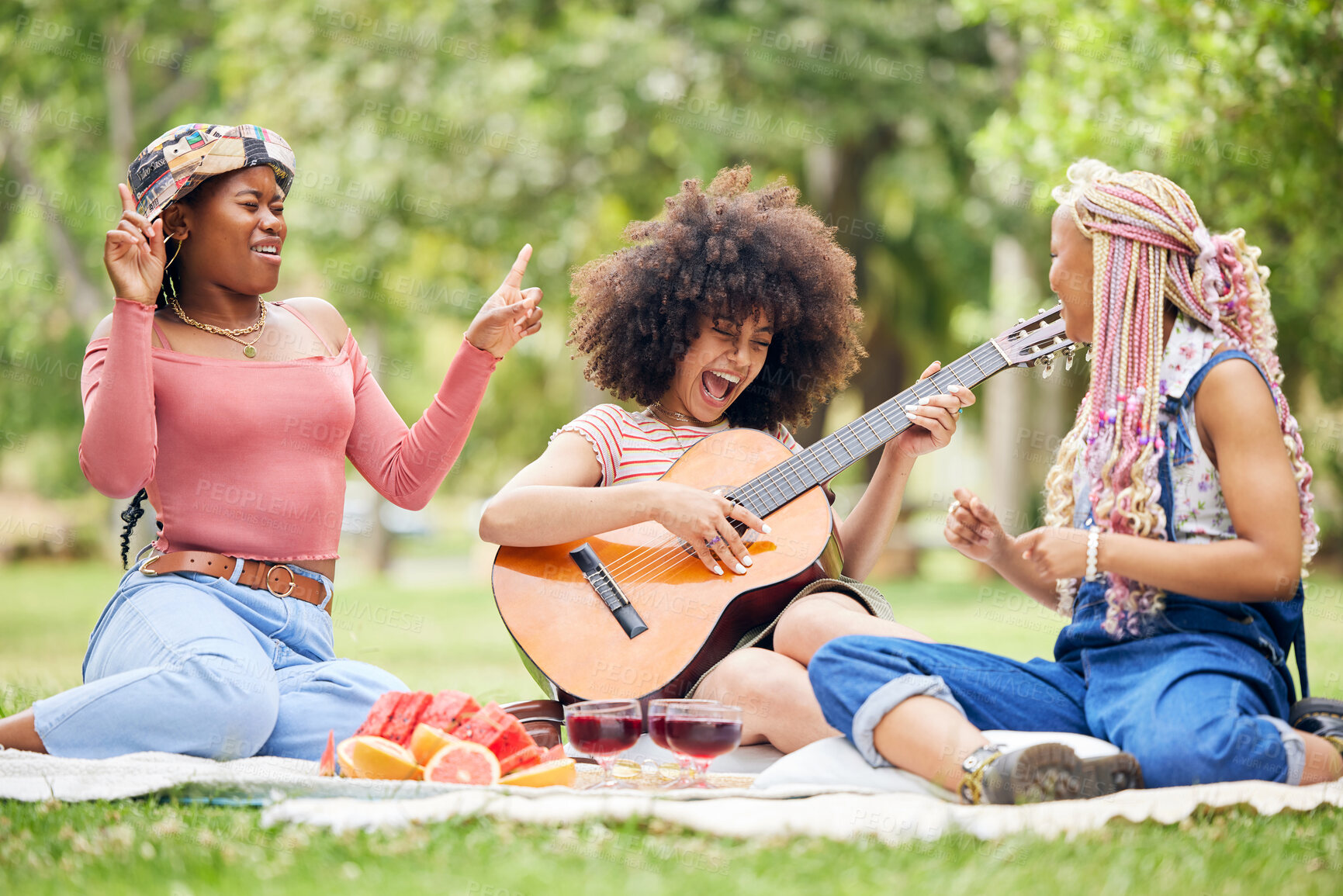 Buy stock photo Black women, friends and picnic in park with guitar playing music, singing and spending time together. Comic, funny and happy ladies with acoustic string instrument, food or wine outdoors for lunch.