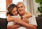 Senior, couple and hug on sofa with smile in home living room together. Elderly, man and woman in retirement with embrace for love, care and bonding on couch in lounge for happiness in house in Rome