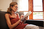 Relax, ecommerce and retirement woman on tablet with glasses reading on internet at home in Canada. Senior person looking at online shopping deals on retail app while resting on living room sofa.

