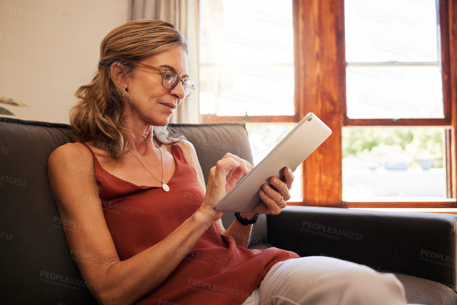 Buy stock photo Relax, ecommerce and retirement woman on tablet with glasses reading on internet at home in Canada. Senior person looking at online shopping deals on retail app while resting on living room sofa.

