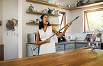 Cleaning, headphones and black woman singing and playing air guitar music with a broom in a house. Fun, playful and happy female enjoying a clean home, kitchen or room while streaming song or radio