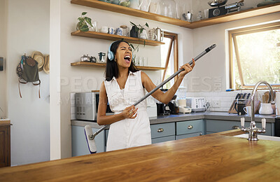 Buy stock photo Cleaning, headphones and black woman singing and playing air guitar music with a broom in a house. Fun, playful and happy female enjoying a clean home, kitchen or room while streaming song or radio