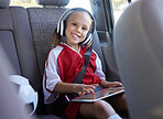 Soccer, car and girl with tablet for music traveling to football practice, exercise and childrens fitness workout. Smile, sports and happy kid in headphones enjoys drive trip to training on a weekend