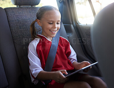 Buy stock photo Happy, girl child and with tablet in car smile, browse online and use social media apps while buckled up. Female kid, use digital device or after practice, share winning soccer match or playing game 