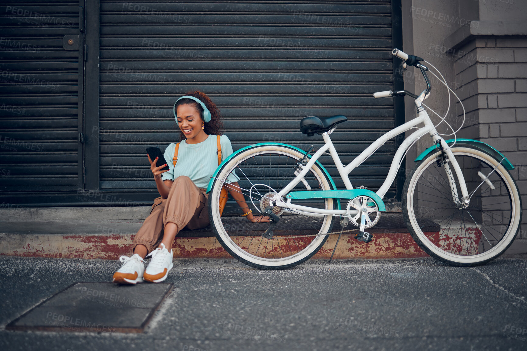 Buy stock photo Bike, woman and headphone with phone in city relax, with bicycle and happy texting, social media apps and chat. Girl, lady and with eco friendly transportation, trendy or edgy look sit on sidewalk