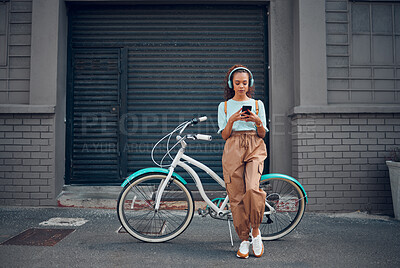 Headphone, woman and phone with bicycle in city listening to music or podcast streaming outdoor in summer with trendy look. Eco friendly transportation for carbon footprint bike using 5g network