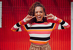 Funny face, happy and black woman with a smile and tongue out with trendy fashion style against a red background. Crazy chic with comic expression while feeling silly, happy and playful outside
