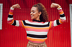 Beauty, fashion and strong with a black woman flexing her muscle or bicep outdoor on a red background. Smile, strength and style with an attractive young female posing for strength or empowerment