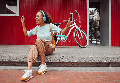 Buy stock photo Black woman in city, listen to music on headphones and relax on street sidewalk waiting for a taxi. Girl streaming podcast, musician online and happy dance song from smartphone 5g internet connection