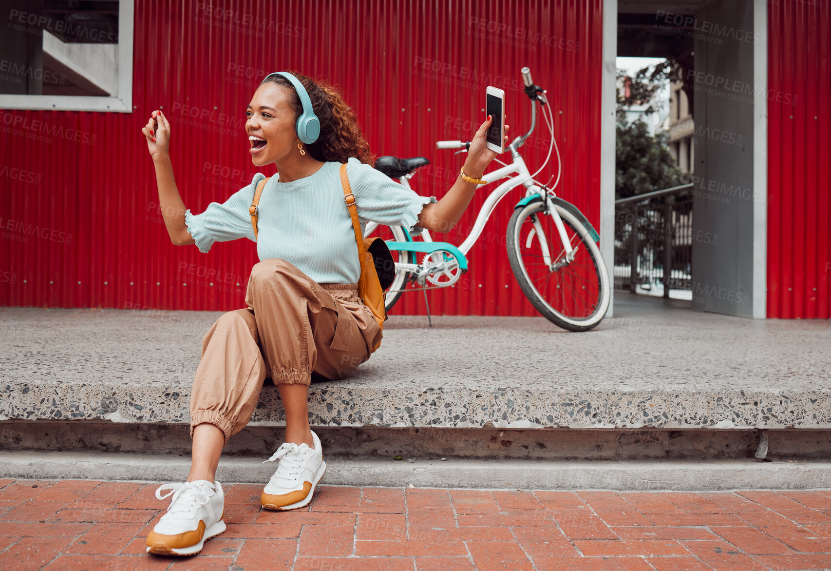 Buy stock photo Black woman in city, listen to music on headphones and relax on street sidewalk waiting for a taxi. Girl streaming podcast, musician online and happy dance song from smartphone 5g internet connection