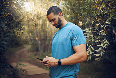 Buy stock photo Sports man, phone and runner in a forest taking a break while texting, communication and typing a message while out for a run. Male athlete out for workout in woods using technology to track health