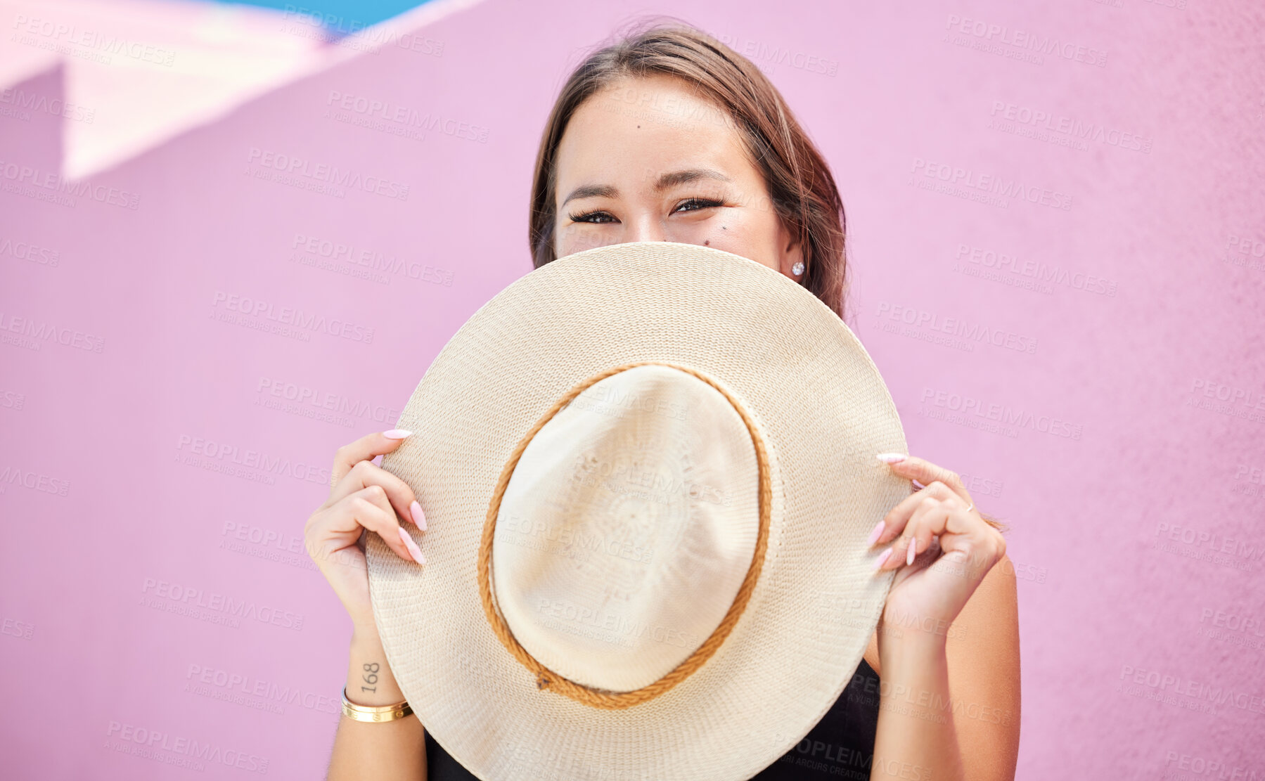 Buy stock photo Travel, fashion and summer hat with a woman tourist in the city on a pastel color pink wall background. Happy, holiday and tourist with a female traveler covering her face with a sunhat in town