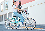 Happy couple, bicycle and city street travel for exercise, fun or adventure outdoor. Black and asian tourist man and woman cycling for carbon footprint on bike in urban town traveling in South Africa