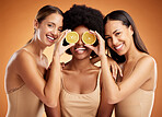 Beauty, friends and diversity with women and lemon for skincare, health and wellness. Happy, aesthetic and fruit with girls in orange background studio for cosmetics, luxury and nutrition lifestyle 