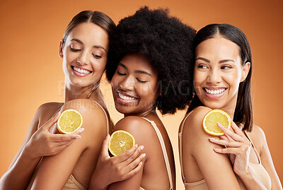 Buy stock photo Skincare, diversity and women, beauty and lemon for health, wellness and nutrition on orange studio background. Friends, smile and happy models with fruit for vitamin c, healthy or glowing skin.
