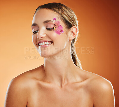 Buy stock photo Flower, face and woman with smile for skincare against a brown mockup studio background. Thinking, happy and creative model with orchid plant for facial wellness, beauty and happiness in spring