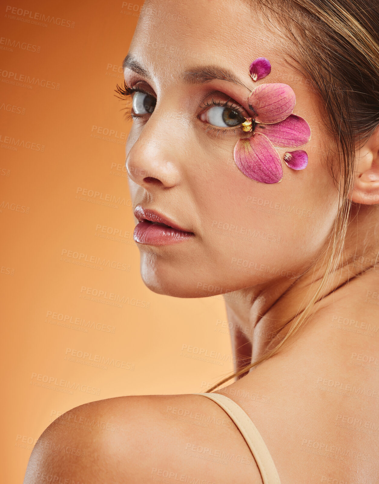 Buy stock photo Model, flower and eye with fashion in portrait with smile for makeup, cosmetics or beauty against backdrop. Woman, orchid and floral art for eyes with skincare, happy and face orange background