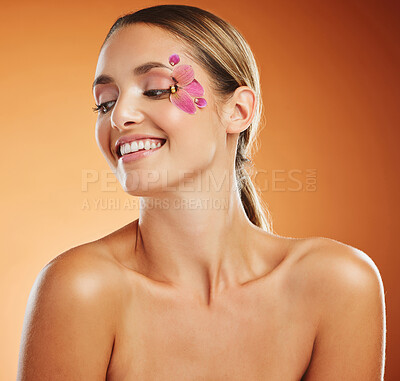 Buy stock photo Flower, creative and woman with smile for face makeup against an orange mockup studio background. Happy, young and thinking model with orchid plant for facial wellness, skincare and body beauty