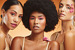 Diversity, beauty and women with flowers for makeup, skincare and cosmetics. Skincare products, spa wellness and group of girls portrait in orange studio with pink orchids for natural beauty products