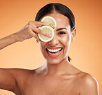 Citrus, beauty and skincare of a woman with a smile holding fruit on her face against a studio background. Portrait of happy female model in healthy vitamins for skin and dental care with teeth