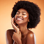 Beauty, skincare and black woman with a facial product or cream on her face in studio with brown background. Smile, afro and happy African model with a natural lotion for glowing smooth and soft skin