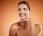 Face, beauty and skincare with a model woman alone, thinking about cosmetics in studio on an orange background. Natural, skin and care with an attractive young female posing with her hand on her chin