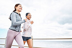 Friends, women and running by ocean, sea or promenade for wellness, fitness and health. Diversity, exercise and happy girls out for a run, cardio workout or training together outdoors by seashore.
