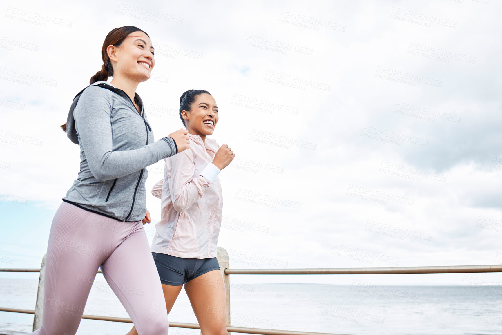 Buy stock photo Friends, women and running by ocean, sea or promenade for wellness, fitness and health. Diversity, exercise and happy girls out for a run, cardio workout or training together outdoors by seashore.
