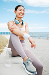 Fitness woman, happy and beach exercise while taking break or rest while out running on promenade with a positive mindset, motivation and goal. Happy asian athlete girl runner outdoor for a workout