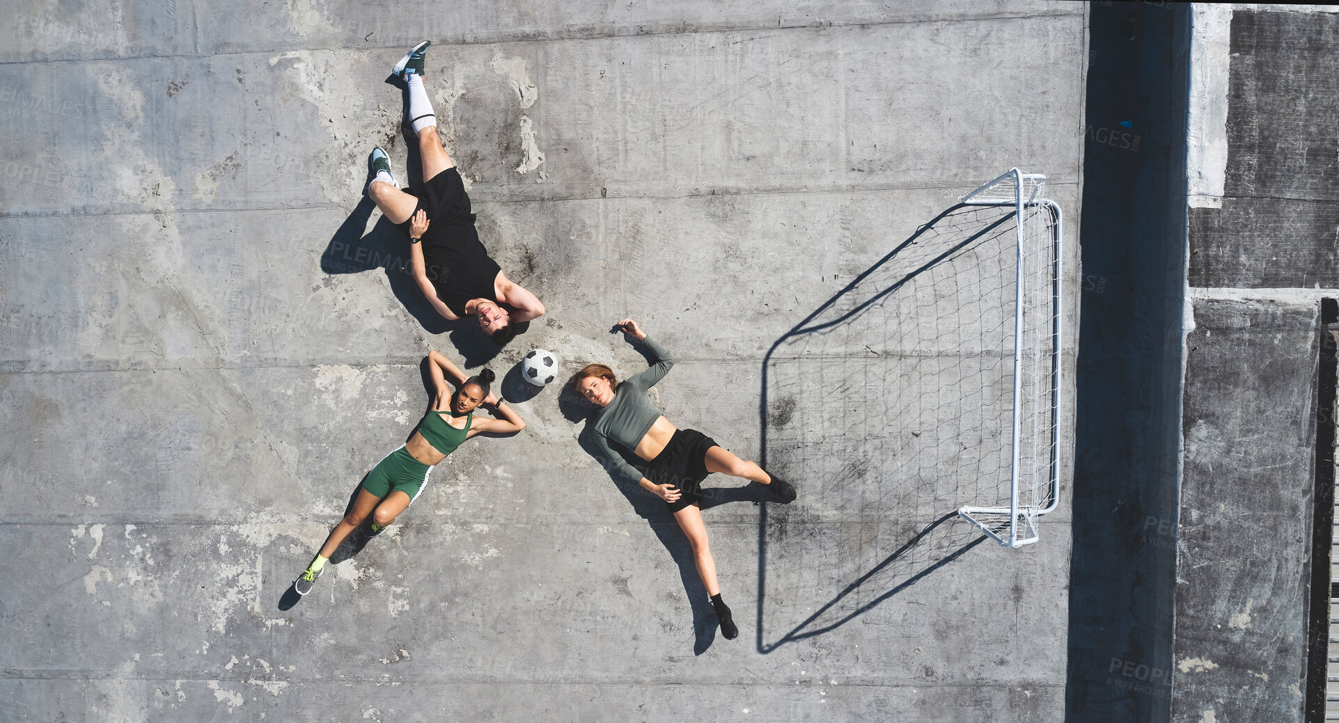 Buy stock photo Top view, soccer ball and friends relax on rooftop together after practice. Football, sports team and man, women and break after exercise match, workout or intense training session on roof in city.